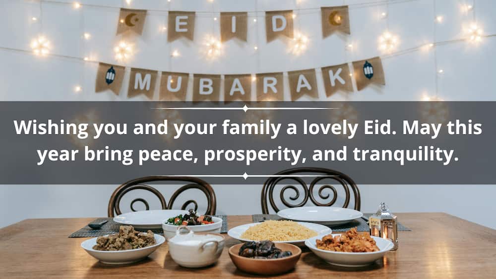 A table with food and decorations on the wall saying Eid Mubarak