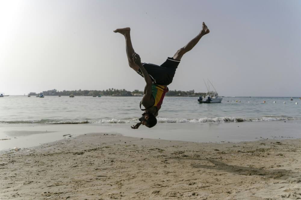 Malick, a 30-year-old acrobat from Guinea, trains on a Dakar beach