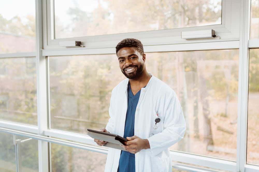 Smiling young male doctor holding digital tablet