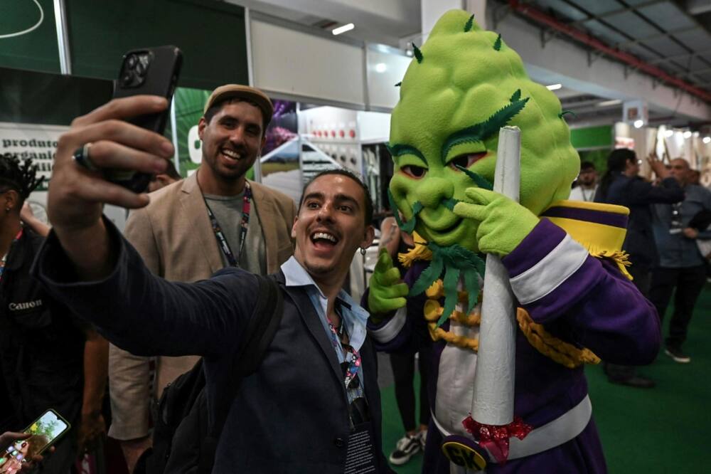 A visitor takes a selfie with a person in a marijuana-themed costume during the ExpoCannabis fair in Sao Paulo, Brazil