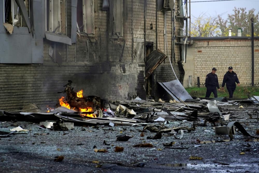 Police officers walk near the site of a car bomb explosion outside a building housing a local TV station in the Russian-held city of Melitopol in southern Ukraine