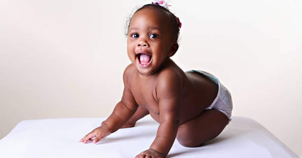Black baby girl in white diaper opening mouth. Photo for illustration.